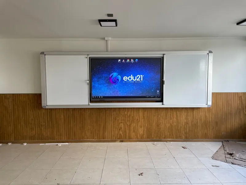 Pizarra GuardCase abierta sobre un muro con revestimiento de madera, junto a la pantalla interactiva