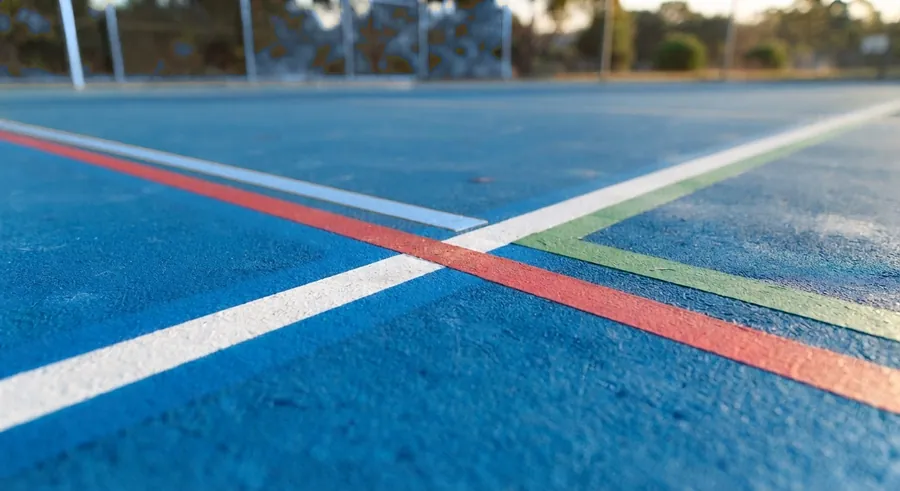 Cruce de líneas blanca, azul, roja y verde sobre una multicancha azul